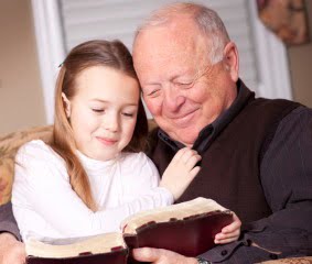 Grandfather reads the Bible to his granddaughter